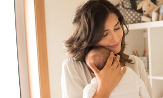 Pretty woman holding a newborn baby in her arms